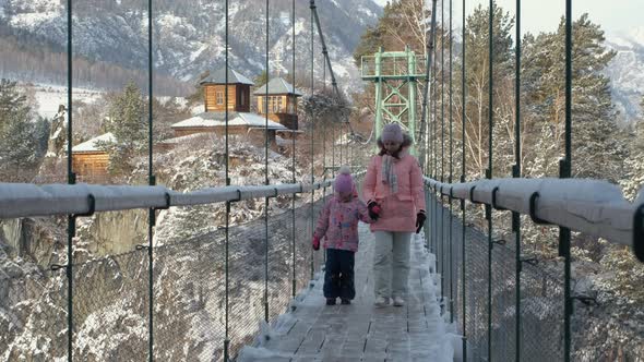 Female with Daughter Walking on Suspension Bridge