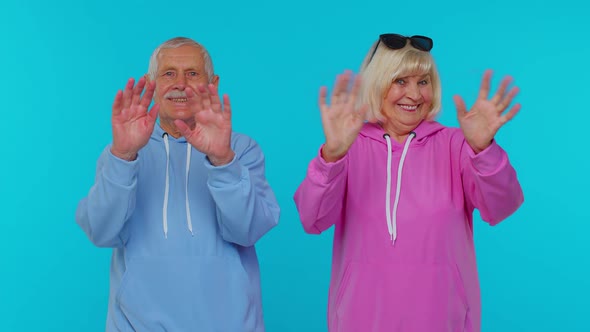 Elderly Granny with Grandfather Smiling Friendly at Camera Waving Hands Gesturing Hello or Goodbye