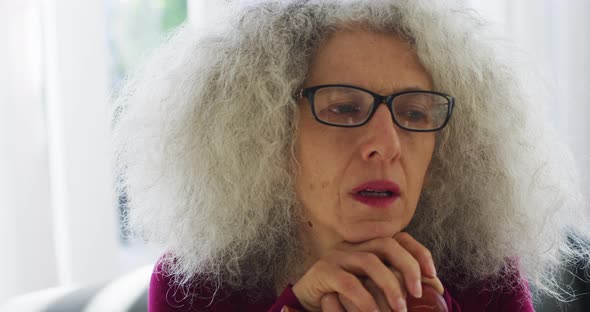 Senior caucasian woman holding walking stick while sitting on the couch at home