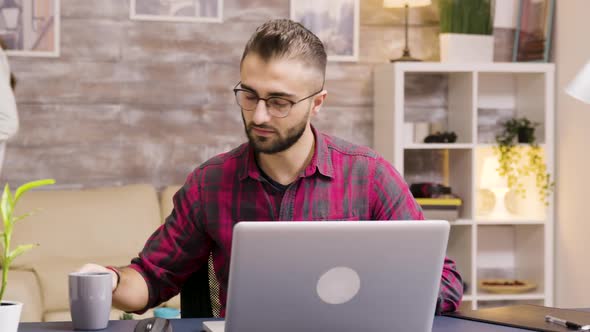 Handsome Entrepreneur Taking a Sip of Coffee While Working on Laptop