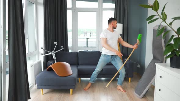 Man Cleaning the House and Having Fun Dancing with a Broom