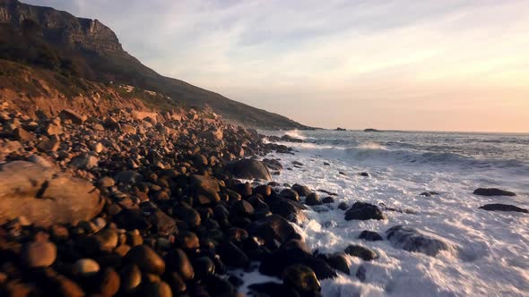 Wild surf with foamy white spray on stony coast line. Powerful atmosphere on a wild South African be