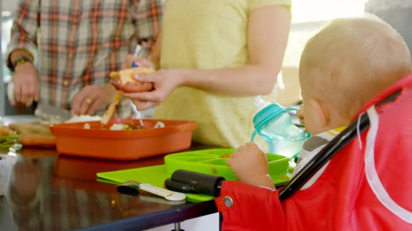 Father and mother preparing breakfast for their baby boy