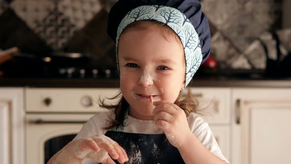 A Small Child in a Chef's Hat Is Playing in the Kitchen with Flour and Dough.