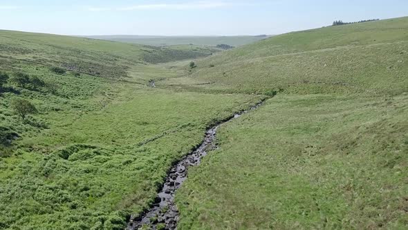 Slow forward tracking aerial over a creek or river to the side of wistmans wood in the heart of Dart