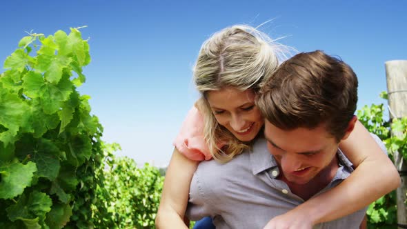 Man giving woman piggy back in vineyard