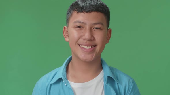 Young Asian Boy Warmly Smiling On Green Screen Background In The Studio alt
