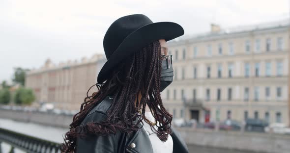 Portrait of Young African Woman in Safety Mask Walking Near City River