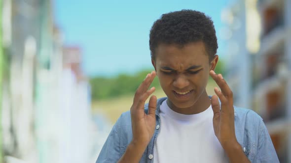 Upset Young Male Suffering Strong Headache, Massaging Temples to Reduce Pain