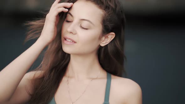 Portrait of Beautiful Young Woman Runs Her Hand Through Hair Looks at Camera