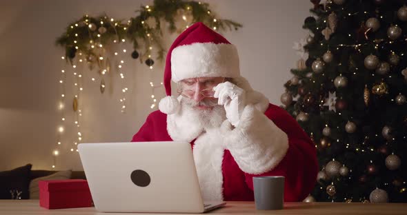 Main Focus on the Negative Emotions and Facial Expressions of Santa Claus Looking at Laptop Monitor