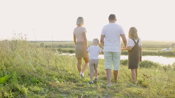 A Family with Children are Walking By the Lake