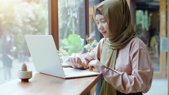 Young beautiful Asian Muslim women enjoying a relaxing moment working and playing with mobile phone