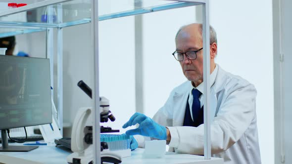 Elderly Man Scientist Doing Research Analysing Liquid in Tube at Laboratory