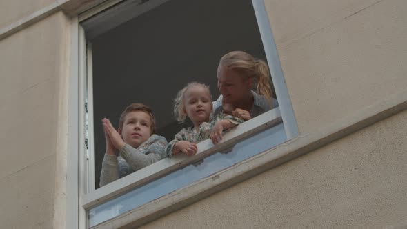 Family in open window during Covid-19 quarantine