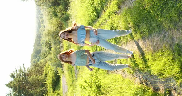 Two Carefree Girls in Stylish Summer Looks Dancing Staging Synchronously