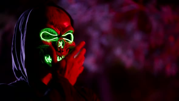 Person in Mask of Glowing Skull in Halloween Party in Night