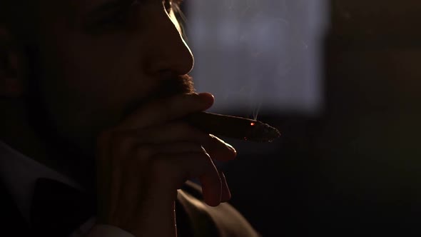 Silhouette of a Handsome Bearded Man Smoking a Cigar Closeup
