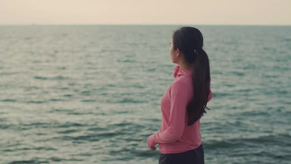 Caucasian woman runner looks at the sea view while standing on the beach.
