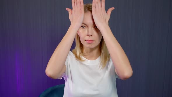 Close-up Portrait of a Blonde Girl Who Is in the Studio on a Blue Background, She Is Engaged in