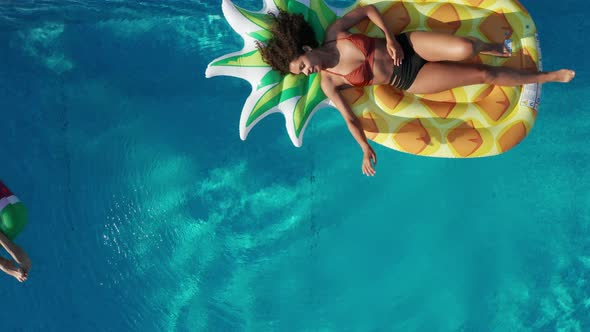 Top View of Joyful Girls Lying on Floaties in Pool