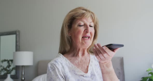 Senior woman talking on smartphone at home