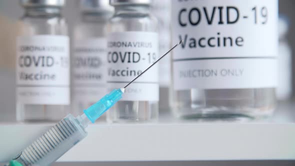 Closeup View of Syringe with Needle and Covid19 Vaccine in the Background