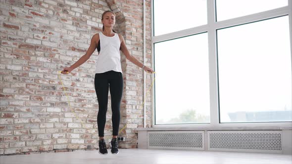 Young and Athletic Woman Warms Up Muscles By Jumping Rope in Fitness Club