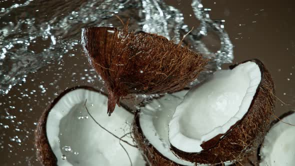 Super Slow Motion Shot of Flying Coconuts and Water Side Splash on Brown Background at 1000Fps