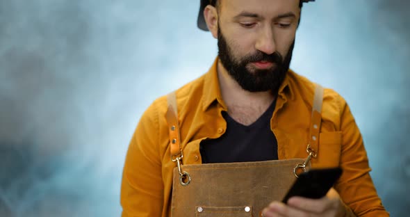 Welder with Phone at the Workshop