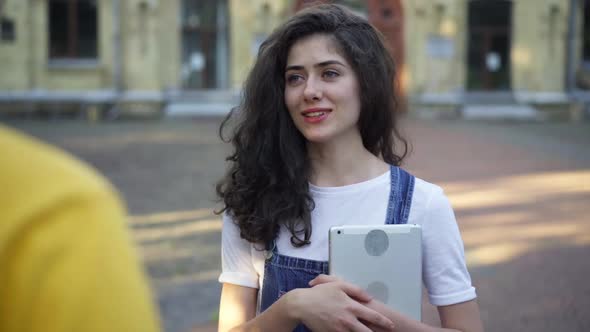 Young Beautiful Woman Talking with Unrecognizable Man Standing with Tablet at College Campus