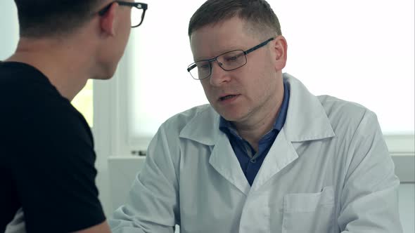 Male Doctor in Glasses Consulting Male Patient