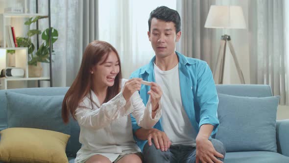 Happy Asian Couple After Checking A Pregnancy Test In Living Room At Home