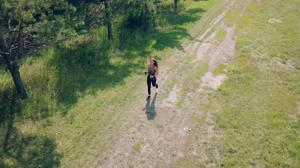 Aerial Shot, Tracking: Young Pretty Girl Goes in for Sports in Morning