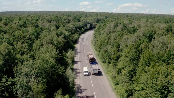 Aerial View of White Truck with Cargo Semi Trailer and Several Cars Moving on Road in the Forest