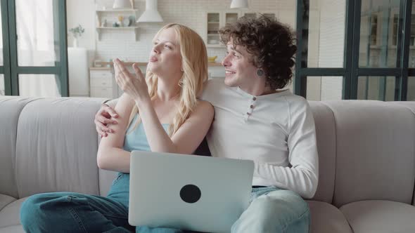 Young Couple On Sofa Looking At Something In Laptop and Dream of Renovating the House