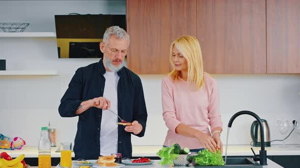 Happy Mature Couple is Having Fun in the Kitchen While Preparing Breakfast