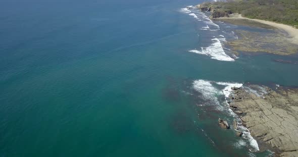 Aerial drone view of the beach, rocks and tide pools in Playa Palada, Guiones, Nosara, Costa Rica.