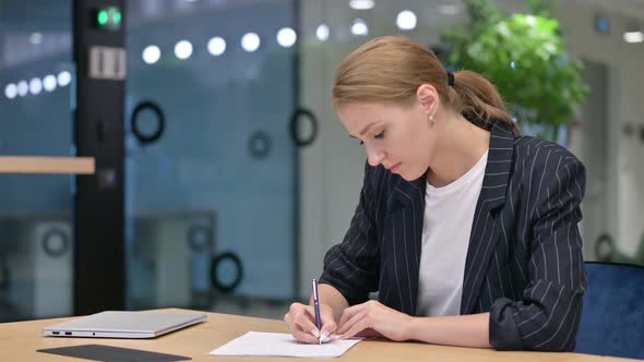 Focused Young Businesswoman Doing Paperwork in Office