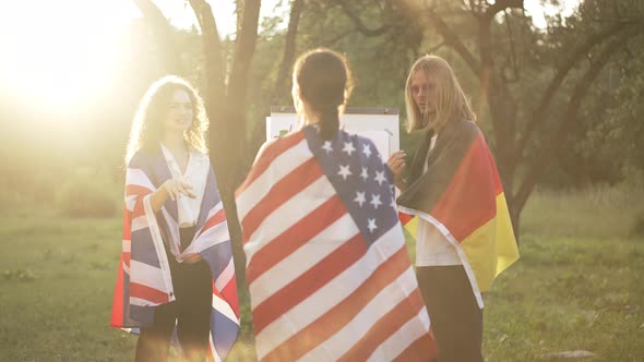 Three Positive Caucasian Colleagues in National Flags Talking in Slow Motion Standing in Sunshine at