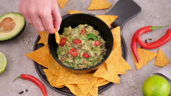 Woman Dips Nachos Chips to Freshly Made Guacamole Dip Sauce in Marble Bowl Mortar