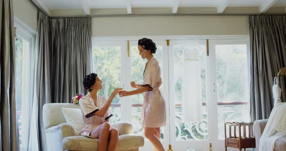 Excited bridesmaids in nightdress and hair rollers tossing a glass of champagne 
