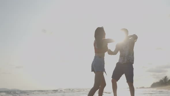 Asian young man and woman having fun, playing on the beach together enjoy holiday honeymoon