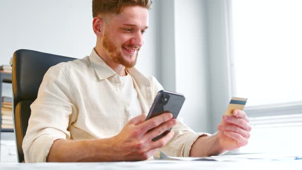 Smiling businessman with beard enters company corporate bank card number