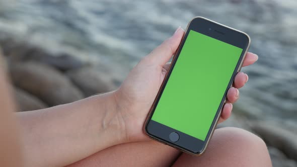 NICE, FRANCE - JULY 2017 Phone with green screen display in female hand  by the sea