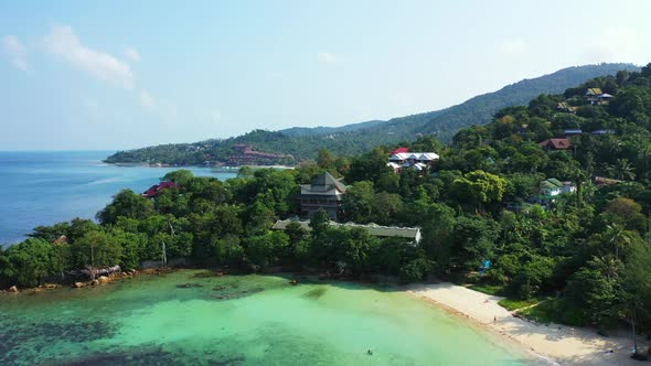 Aerial drone shot landscape of paradise coastline beach holiday by blue green lagoon with white sand