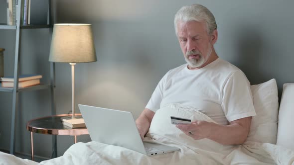 Online Shopping on Laptop By Old Man in Bed 