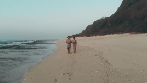 Portrait of Beautiful Girl and Young Man Walking on the Beach Drone Aerial View