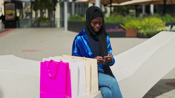 Trendy Muslim Woman Browsing Smartphone During Shopping