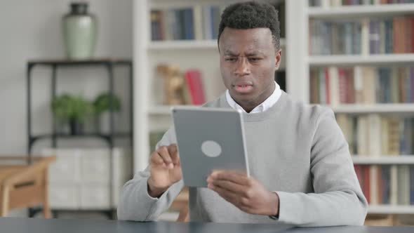 African Man Reacting to Loss on Tablet While Sitting in Library